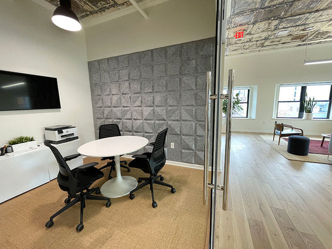 Small meeting room with gray Quad acoustic wall panels for improved speech clarity and sound absorption.