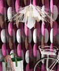 White Bendant Lamp in front of a pink, brwon and white room divider with bicycle and a bag.