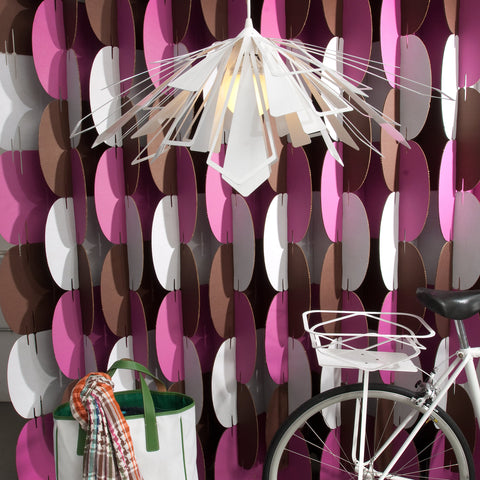 White Bendant Lamp in front of a pink, brwon and white room divider with bicycle and a bag.