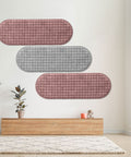 Decorative wall panels in pink and gray on a white wall with a wooden shelf and plants below.