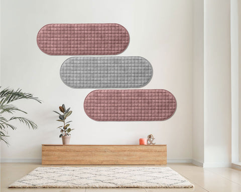 Decorative wall panels in pink and gray on a white wall with a wooden shelf and plants below.